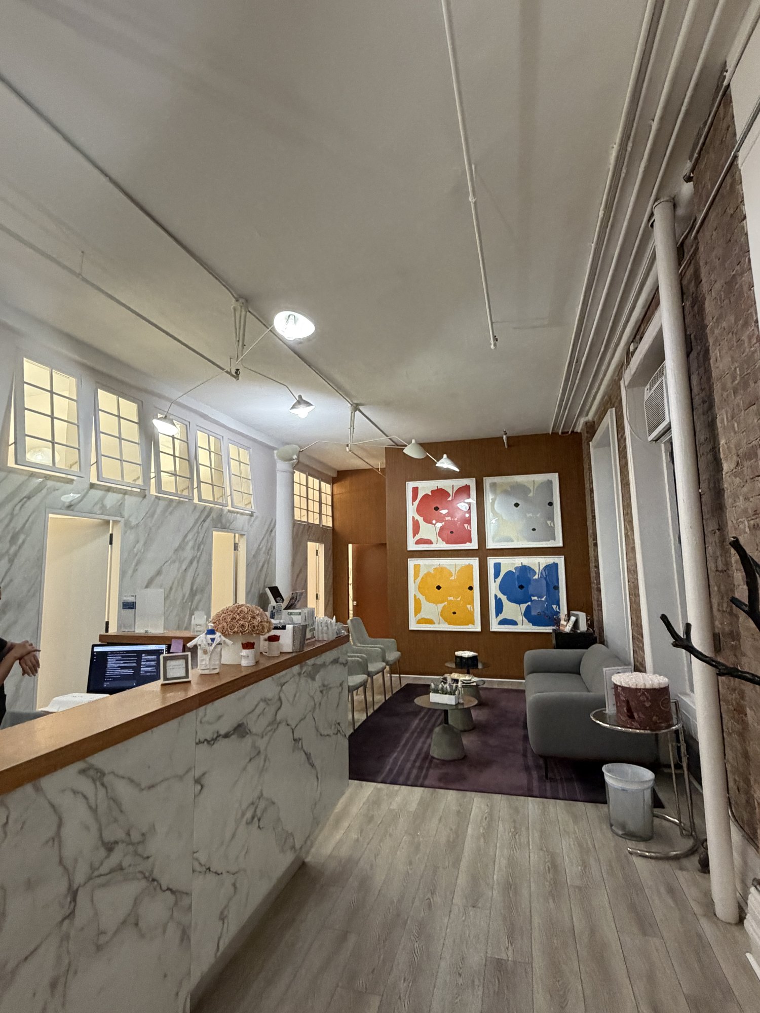 Sunlit waiting room with tall Broadway windows, exposed brick ceiling and marble counter